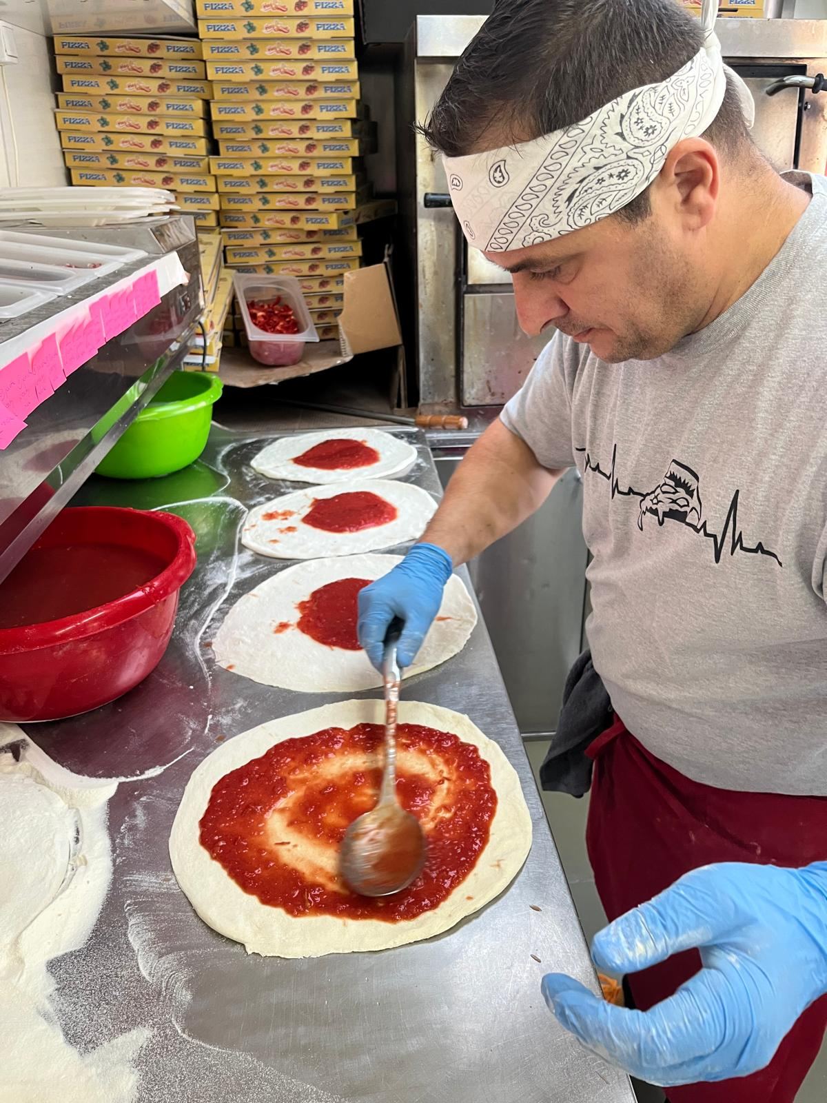 Przygotowanie pizzy — rozprowadzanie sosu pomidorowego