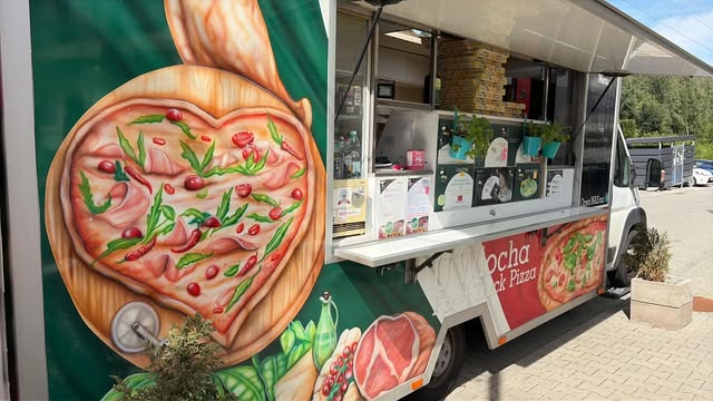 Okno wydawcze food trucka z menu i pizzą w kształcie serca